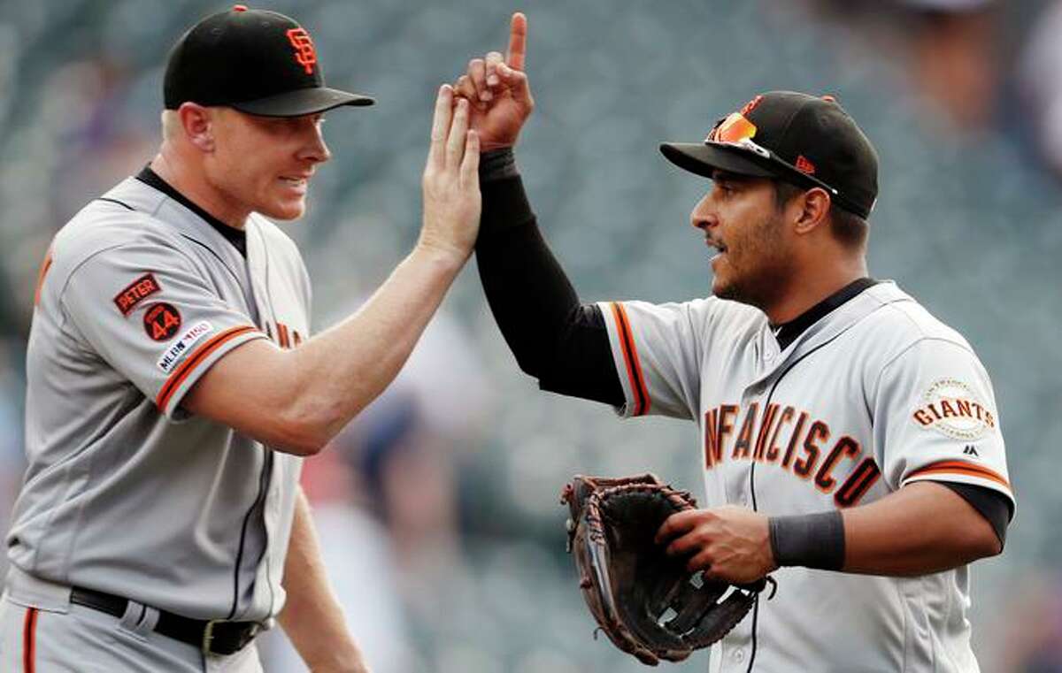 Above, reliever Mark Melancon (left) is met by shortstop Donovan Solano at game’s end.