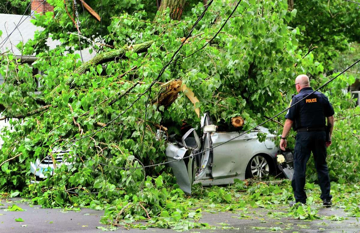 A car, with an occupant who was rescued from, is still covered by a tree which fell on it along Park Ave Bridgeport, Conn., on Wednesday July 17, 2019. Due to live wires that fell, Bridgeport and Fairfield firefighters had to wait as long as an hour before they could remove the victim.