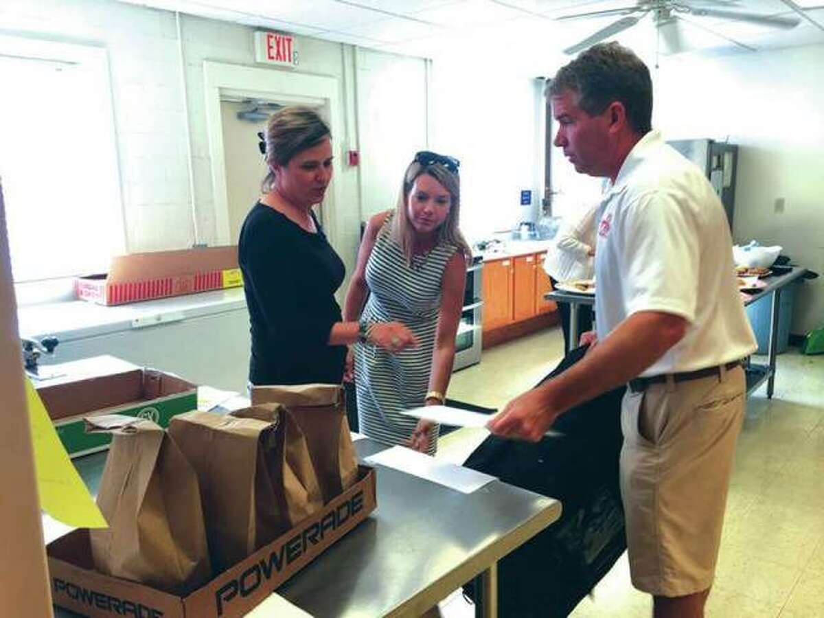 Madison County Board members Ann Gorman, left of Edwardsville, and Erica Conway-Harriss, center, of Glen Carbon, helps Edwardsville Mayor Hal Patton load meals for delivery last September as part of the “Big Wheels Deliver Meals” program being conducted at the Main Street Community Center. Local leaders volunteered their time to take part in the MSCC’s Meals on Wheels program, delivering lunches to area seniors and disabled adults. “Big Wheels” made its debut last year for one week in September and is being expanded this year to run for the entire month.