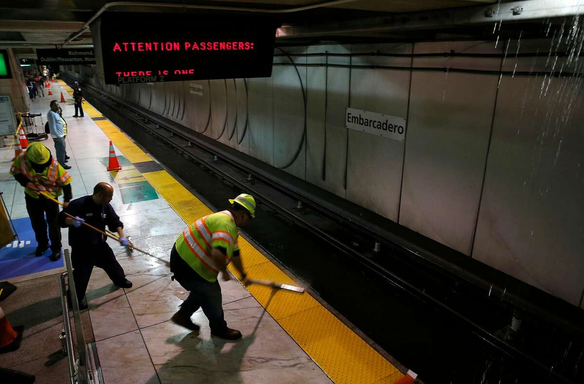 Maintenance crews clear water from the BART train platform at the Embarcadero station as water continues to rain down from a broken pipe on the Muni level above in San Francisco, Calif. on Thursday, July 18, 2019.