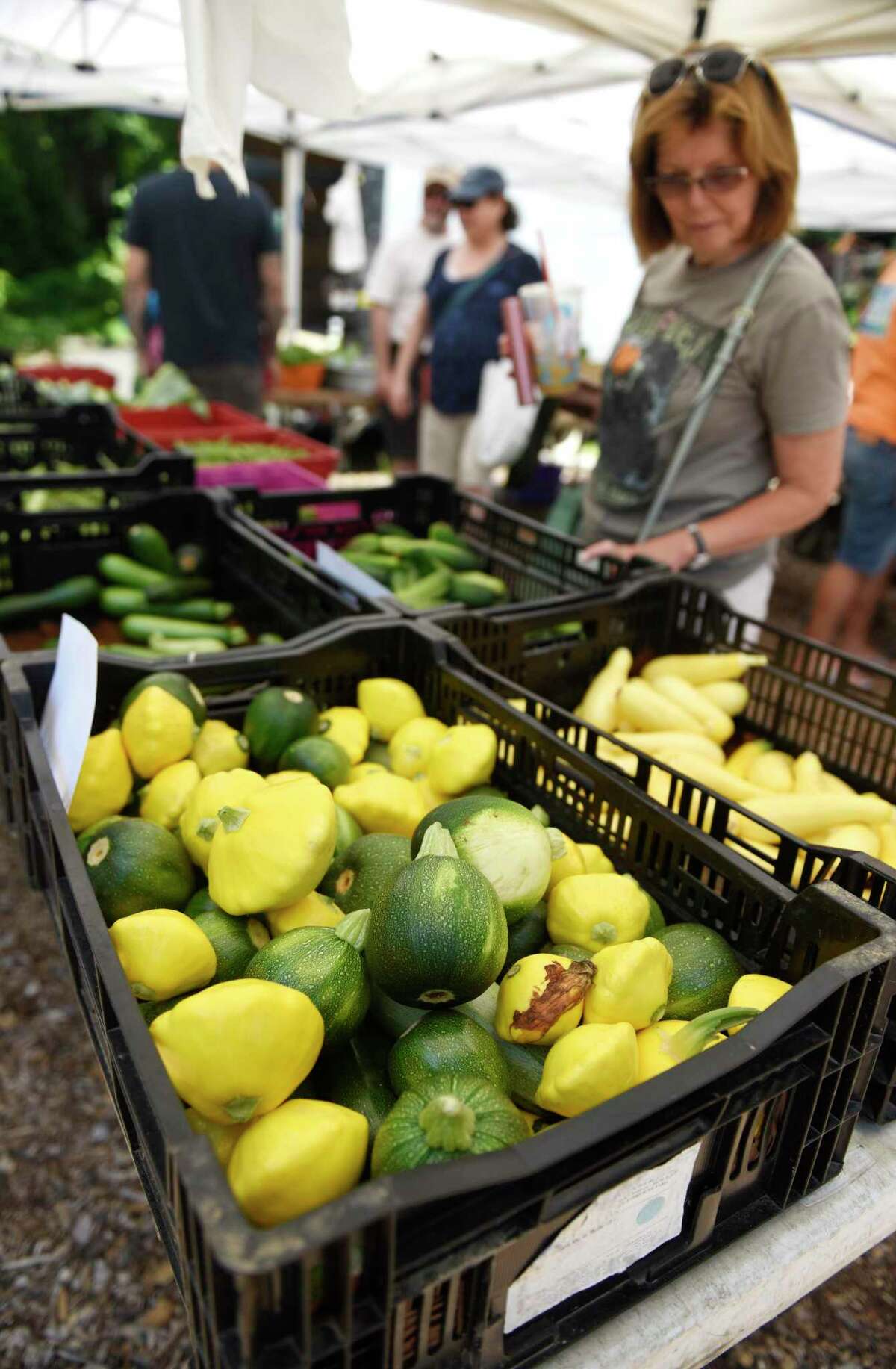 Customers browse the Smith's Acres stand at the Stamford Museum & Nature Center Sunday Farm Market in Stamford, Conn. Sunday, June 30, 2019.