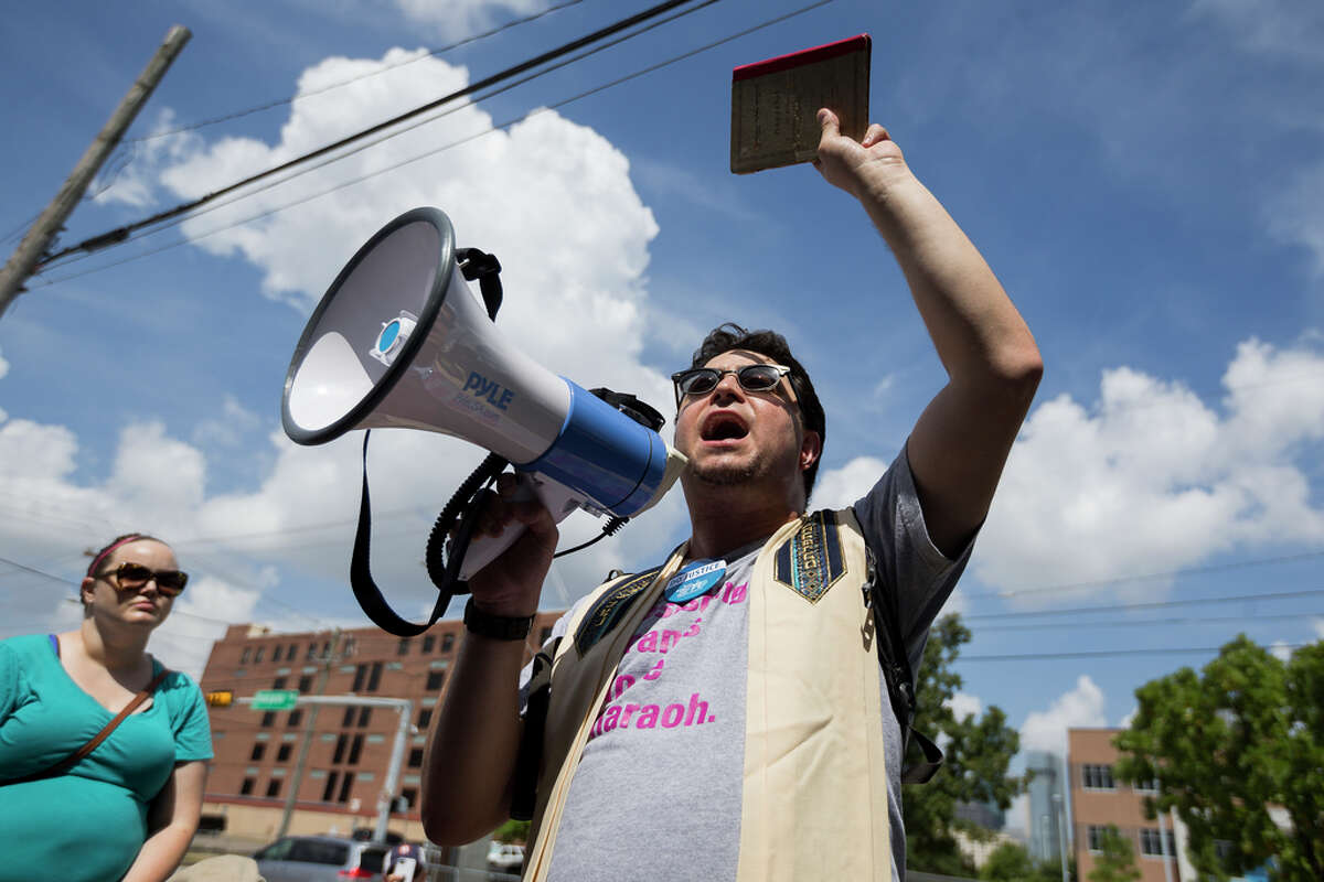 Rabbi Josh Fixler protests against the Southwest Key Detention Center on Emancipation Ave in Houston, Sunday, July 21, 2019. Fixler holds the Haggadah that belonged to his grandfather in Berlin. Never Again Is Now-Houston organized the protest against ICE and the detention center.