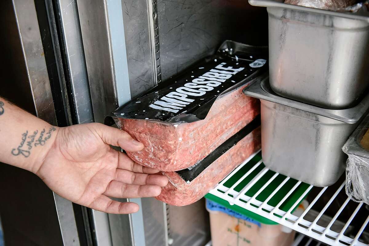 Chef George Mullen shows bulk packages of Impossible Burger "meat" in a cooler at Violet's restaurant in San Francisco, Calif., on July 21st, 2019. Impossible Foods is distributing Impossible Burgers to independent restaurants again after a two-month dry spell, which coincided with its expansion to Burger Kings nationwide.