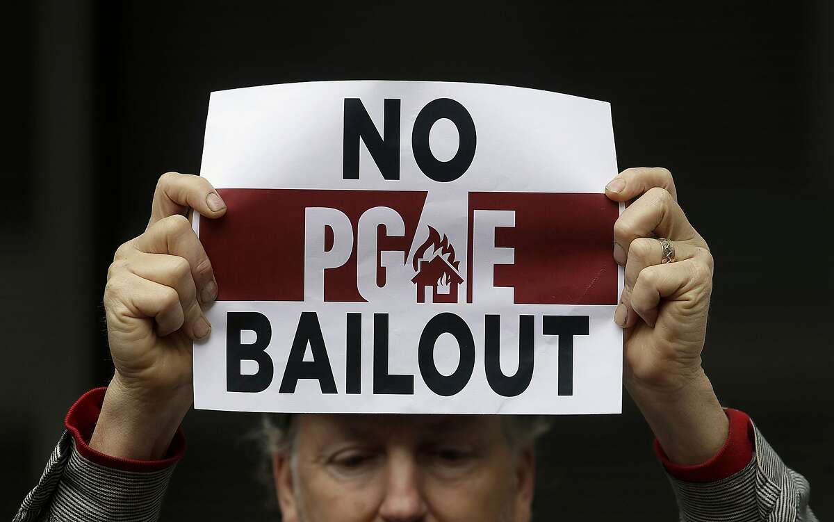 FILE - In this Jan. 28, 2019 photo, a man holds a sign at a rally before a California Public Utilities Commission meeting in San Francisco. A Wednesday, July 10, 2019, report in the Wall Street Journal says Pacific Gas & Electric, which is blamed for some of California's deadliest recent fires, knew for years that dozens of its aging power lines posed a wildfire threat but avoided replacing or repairing them. PG&E says it disagrees with the Journal's conclusions but says it�s "taking significant actions to inspect, identify, and fix" safety issues. (AP Photo/Jeff Chiu, File)