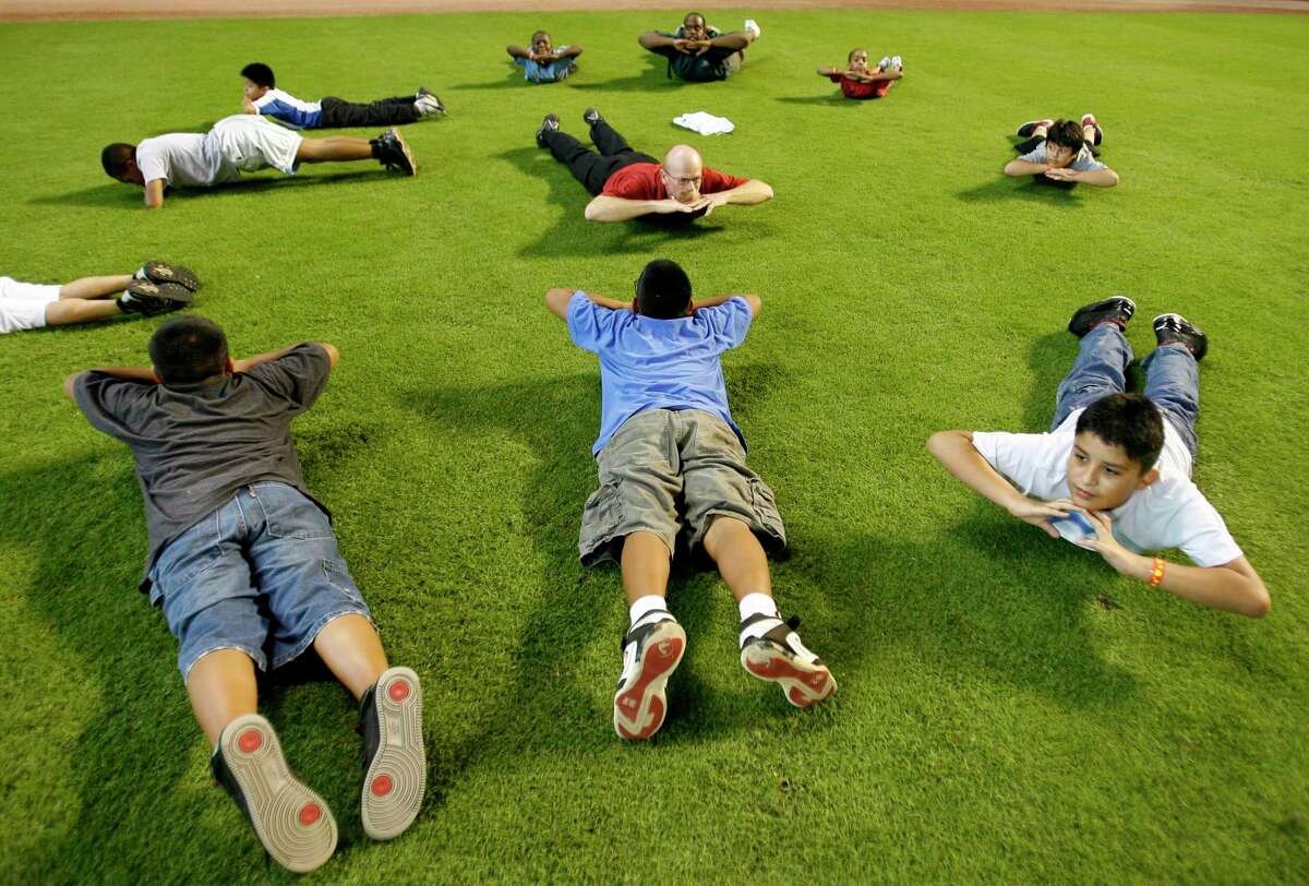 Astros Assistant Athletic Trainer, Rex Jones (in the center with red shirt) leads a group of kids from the Boys and Girls Club to stretching exercises during the 2009 National “PLAY” event, hosted by the Houston Astros, at Minute Maid Park. PLAY stands for Promoting a Lifetime of Activity for Youth and is a public awareness campaign of the Professional Baseball Athletic Trainers Society (PBATS). ( Karen Warren / Chronicle )