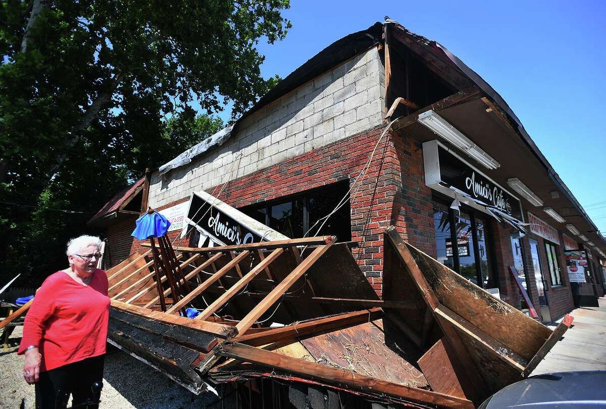 Amici’s Cafe customer Janet Aldrich, of Milford, surveys the damage after a large wooden awning collapsed on picnic tables outside the business at 784 Boston Post Road in Milford, Conn. on Monday, July 22, 2019.