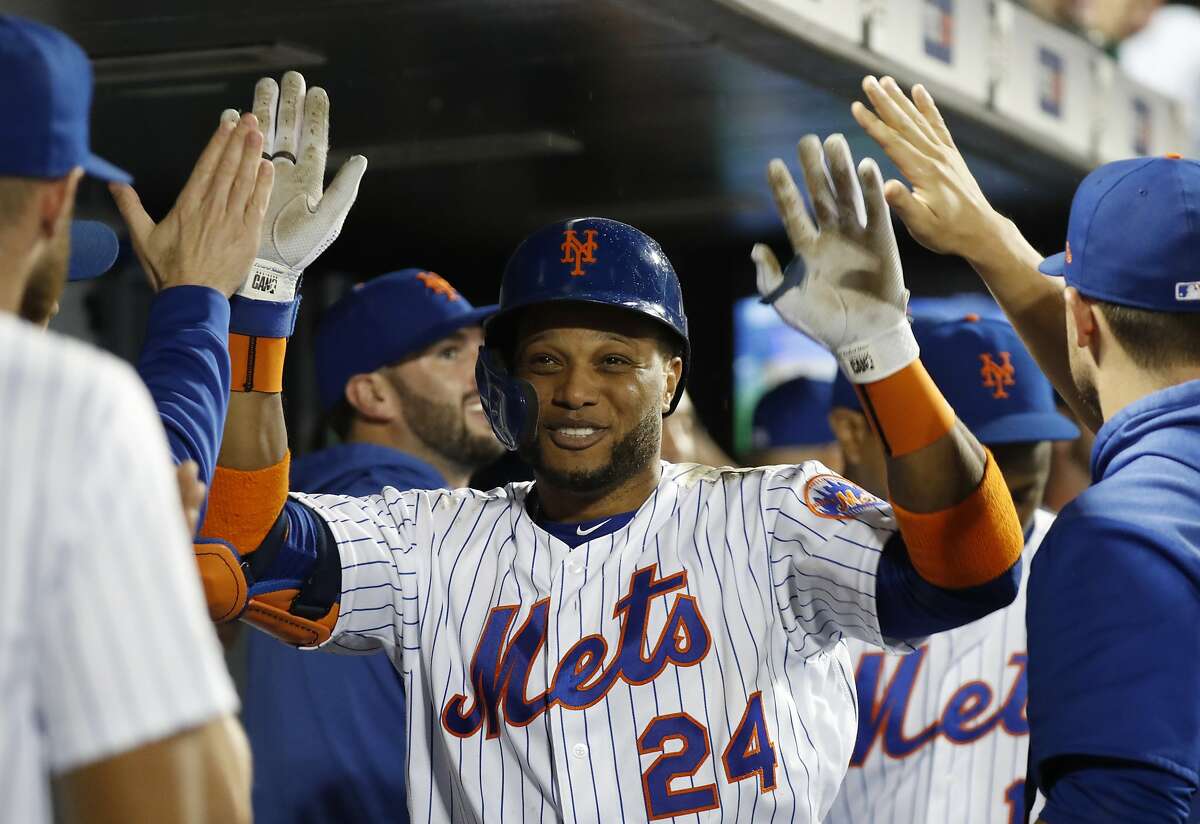 Teammates in the dugout congratulate New York Mets' Robinson Cano after the third of Cano's three home runs in a baseball game against the San Diego Padres, Tuesday, July 23, 2019, in New York. The last blast came against San Diego Padres relief pitcher Logan Allen in the seventh inning. It was the first time in Cano's long career that he has hit three home runs in one game. (AP Photo/Kathy Willens)