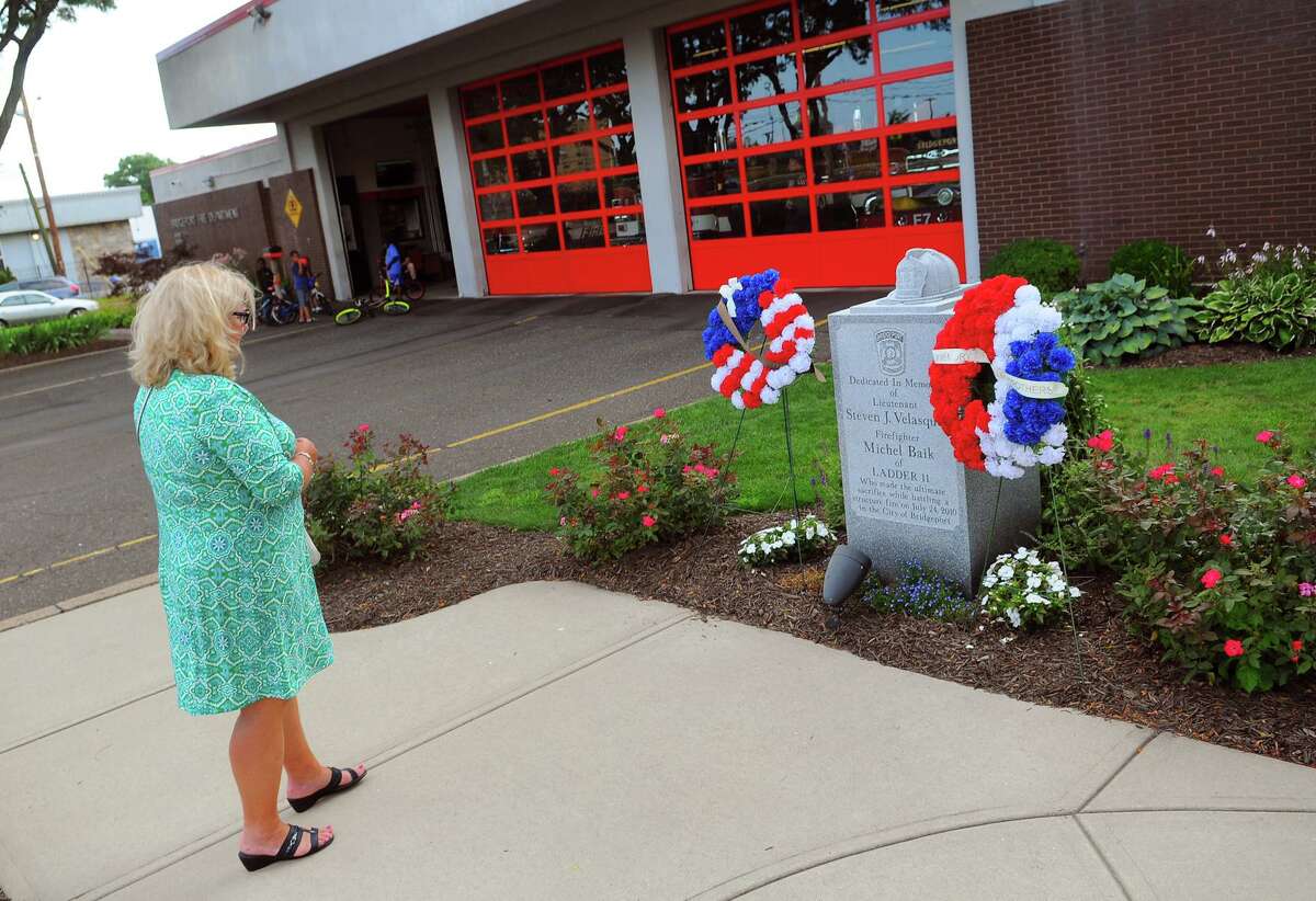 A relative of firefighter Michel Baik stops by the memorial to him and another firefighter, Lt. Steven Velasquez, on the anniversary of their death at the fire station on Ocean Terrace in Bridgeport, Conn., on Wednesday July 24, 2019. The firefighters died while fighting a fire on Elmwood Ave, in Bridgeport, on July 24, 2010.