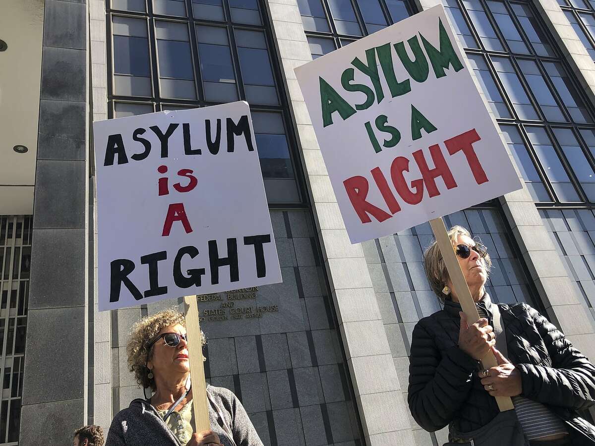 Protestors hold signs that read " Asylum is a Right" outside of the San Francisco Federal Courthouse on Wednesday, July 24, 2019 in San Francisco, Calif. A federal judge said Wednesday that the Trump administration can enforce its new restrictions on asylum for people crossing the U.S.-Mexico border while lawsuits challenging the policy play out. (AP Photo/Haven Daley)