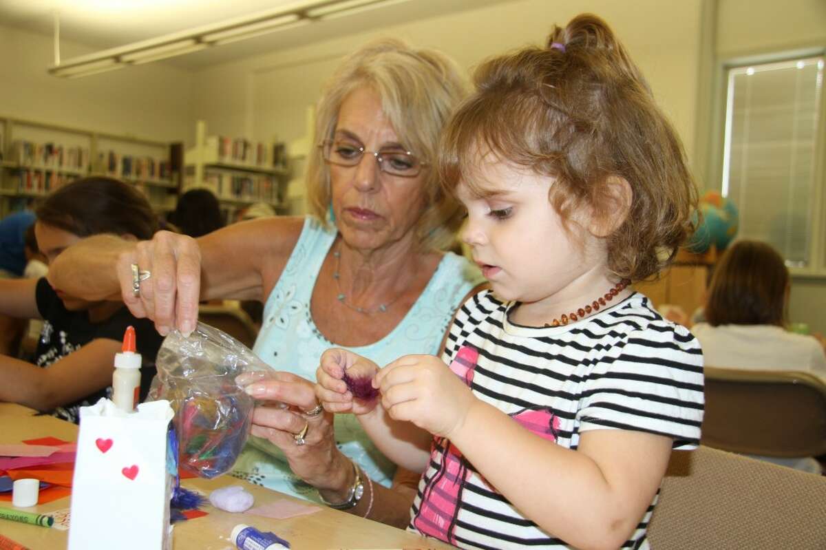 photo_credit="" A LITTLE HELP: Mary Jo Chaput helps her granddaughter, Myah Chaput, 2, pick out a feather to glue to her birdhouse. More than 25 children created birdhouses out of small milk containers on Tuesday at the Big Rapids Community Library. (Pioneer photos/Jonathan Eppley)