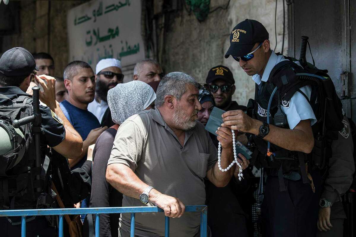 An Israeli police officer checks the ID of a Palestinian man at a checkpoint outside Jerusalem’s Old City on July 28, 2017.