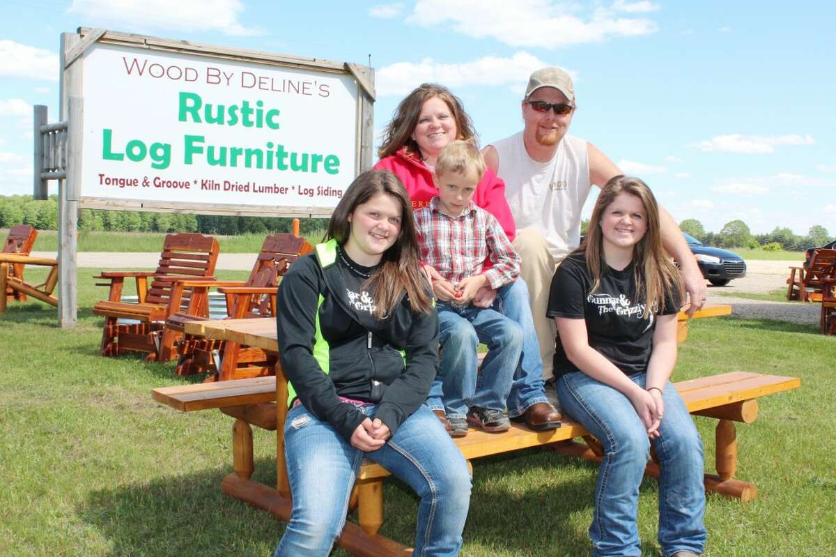 RUSTIC HOME DESIGN: Wood By Delines owners Lewis and Summer offer a variety of rustic log furniture for both indoor and outdoor use. The business is located on the corner of U.S. 10 and 170th Ave. in Hersey. Here, the Delines sit with their children (from left) Olivia, Torigan and Talon. (Pioneer photo/Karin Armbruster)