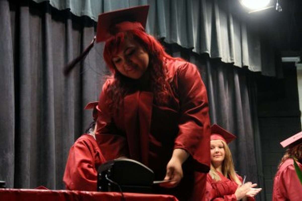 FAREWELL: Mosaic School graduates punch their time cards for the final time at graduation on Wednesday. The alternative school is formatted like a job, with students punching a time card for class and having the option to advance to salary status.