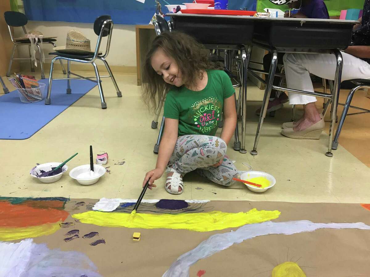 Makaela Martinez, 6, uses yellow paint to add sand to a seascape on July 24, 2019.