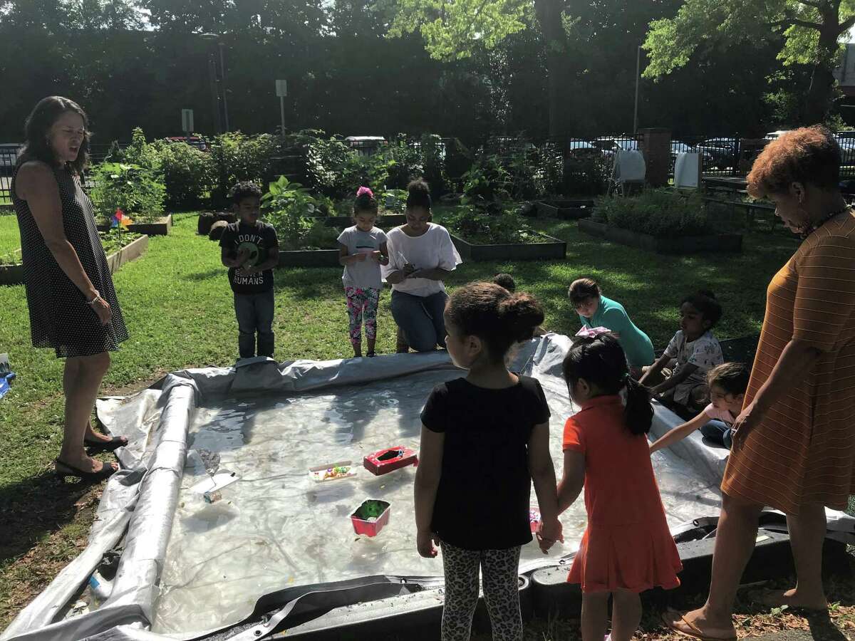Students at a play-based summer learning program at Conte West Hills School float boats made of plastic containers on July 24, 2019.