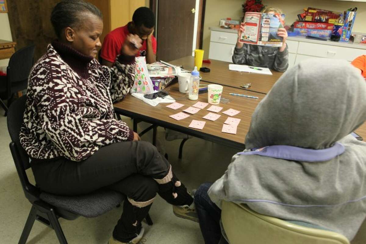 LEARNING SOMETHING NEW: Sylvia is taught how to play a card game by her daughter. Sylvia is staying at Our Brother's Keeper with her husband, children and a grandchild. (Pioneer photos/Emily Grove-Davis)