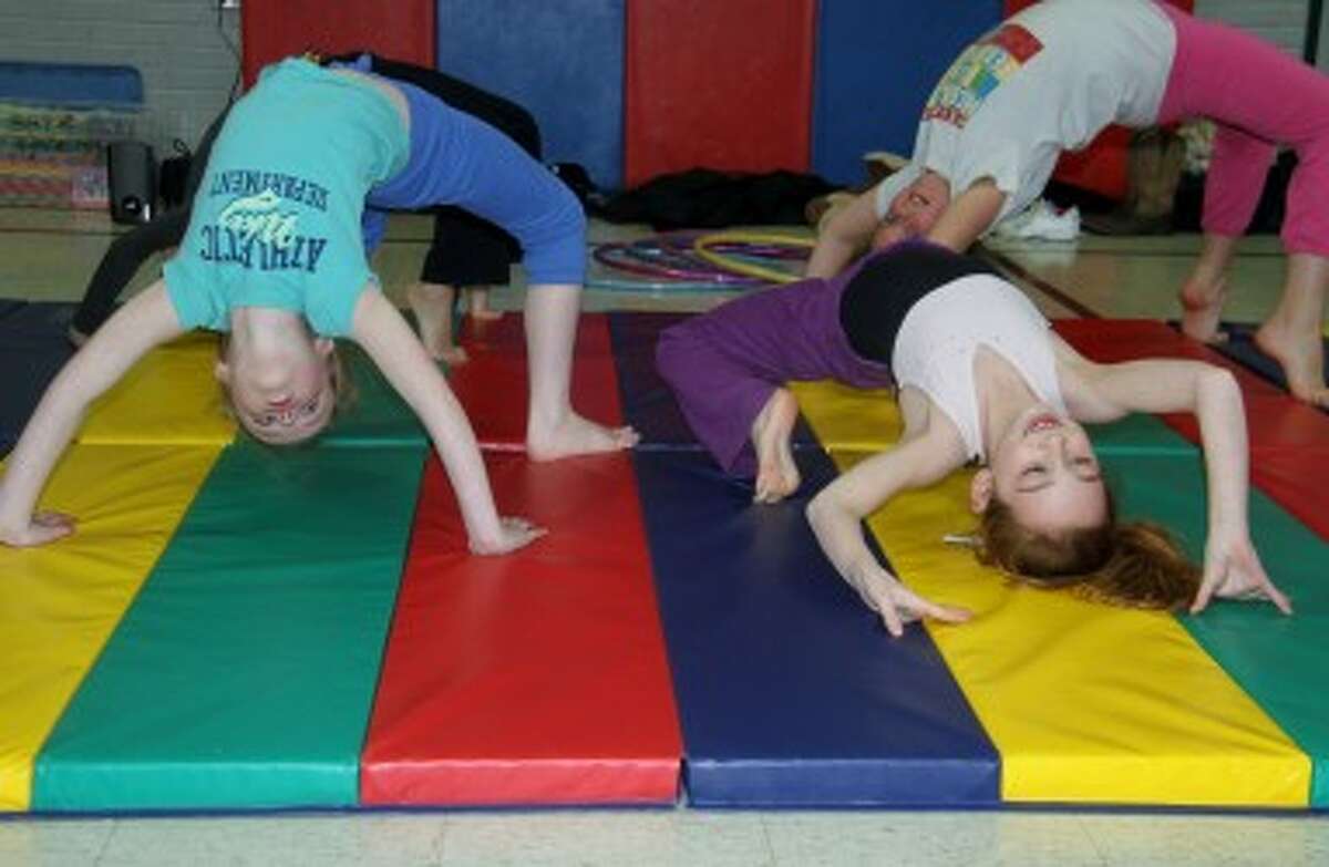 YOUNG GYMNASTS: Several stations for different age groups were set up in the gym at Brookside Elementary School on Tuesday, where older girls taught basic gymnastics moves.