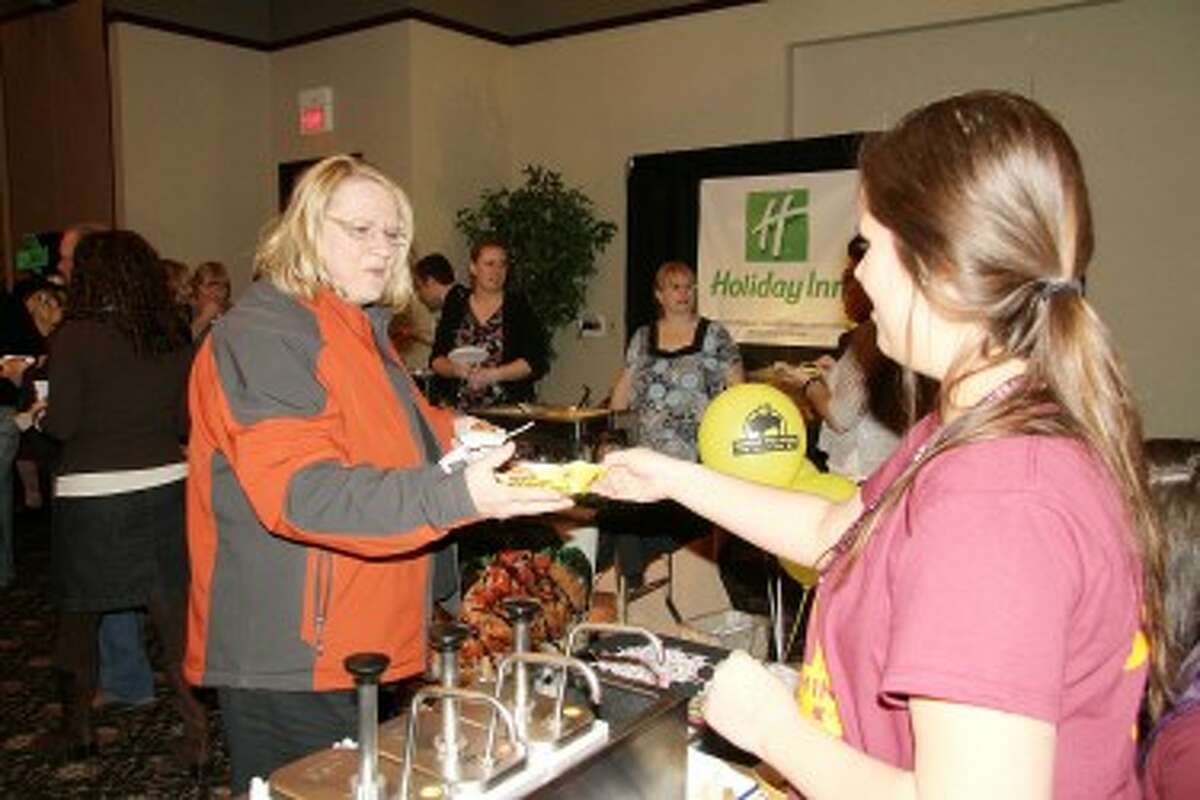 TASTE OF MECOSTA: Mary Ann Lenon gets a basket of chicken from the Buffalo Wild Wings table at the 2012 Taste of Mecosta. This year’s event will be held on Feb. 12 at the Holiday Inn Hotel and Conference Center.