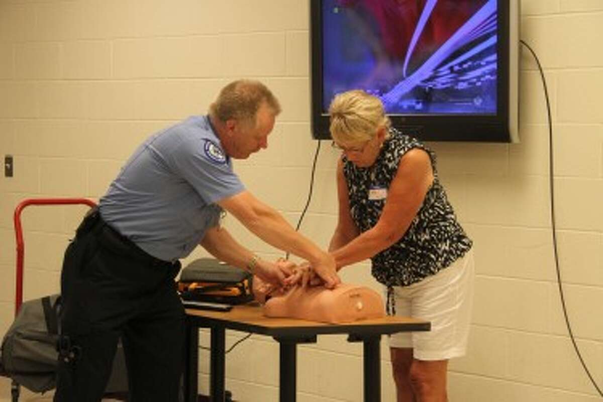 HELPING HANDS: Mecosta County Emergency Medical Services paramedic Dan Farrow helps Carol Ells position her hands on a CPR dummy to properly give chest compressions.