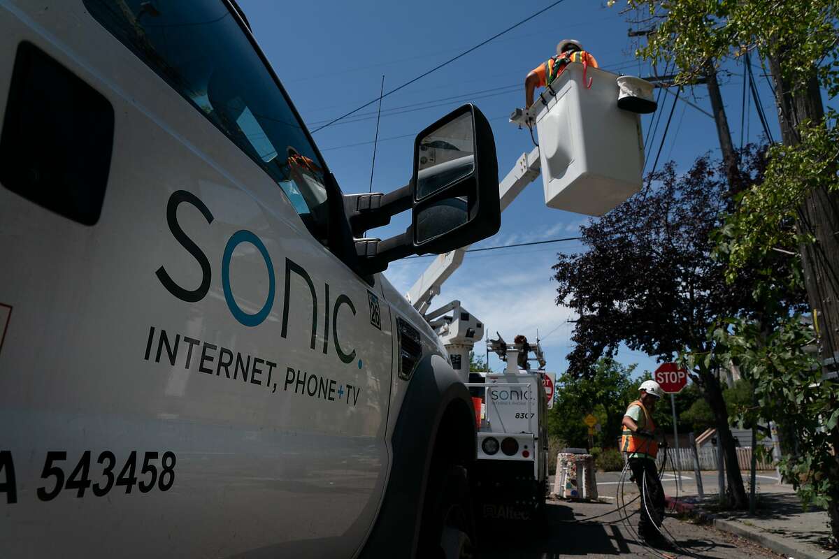 Sonic employees Francis Barton (top) and Darrin Dailey install new fiber optic cables at a box on Fairview St. and California St. that can provide 500 homes with symmetrical Gigabit speeds on Thursday, July 25, 2019, in Berkeley, Calif.