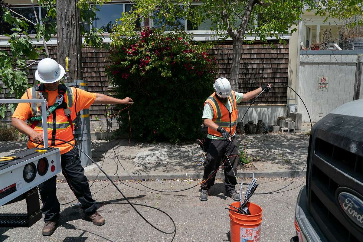Sonic employees Francis Barton and Darrin Dailey installs new fiber optic cables at a box on Fairview St. and California St. that can provide 500 homes with symmetrical Gigabit speeds on Thursday, July 25, 2019, in Berkeley, Calif.
