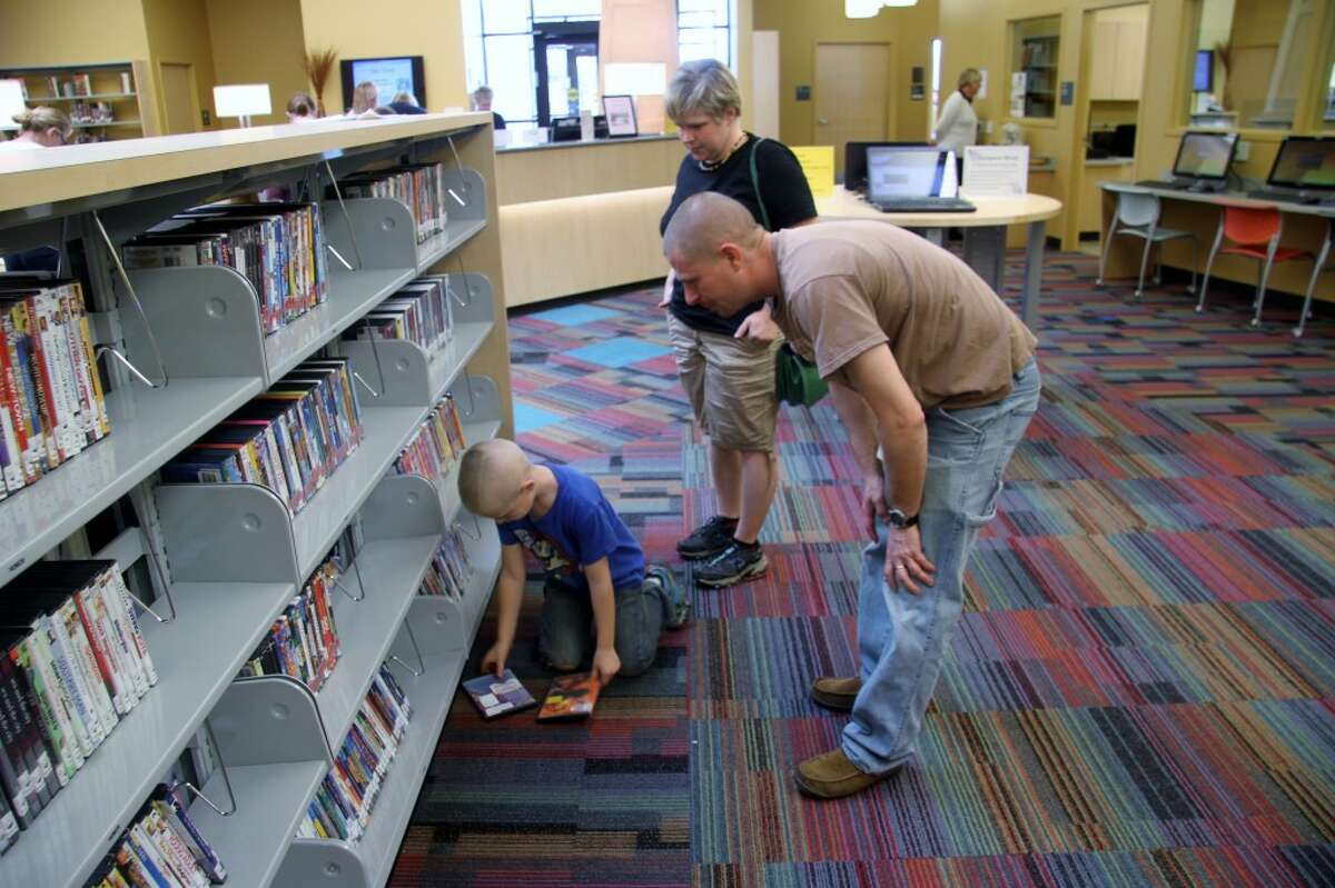 LIBRARY STOP: Max Wright, 6, picks out movies with his parents at the Morton Township Library on Thursday.