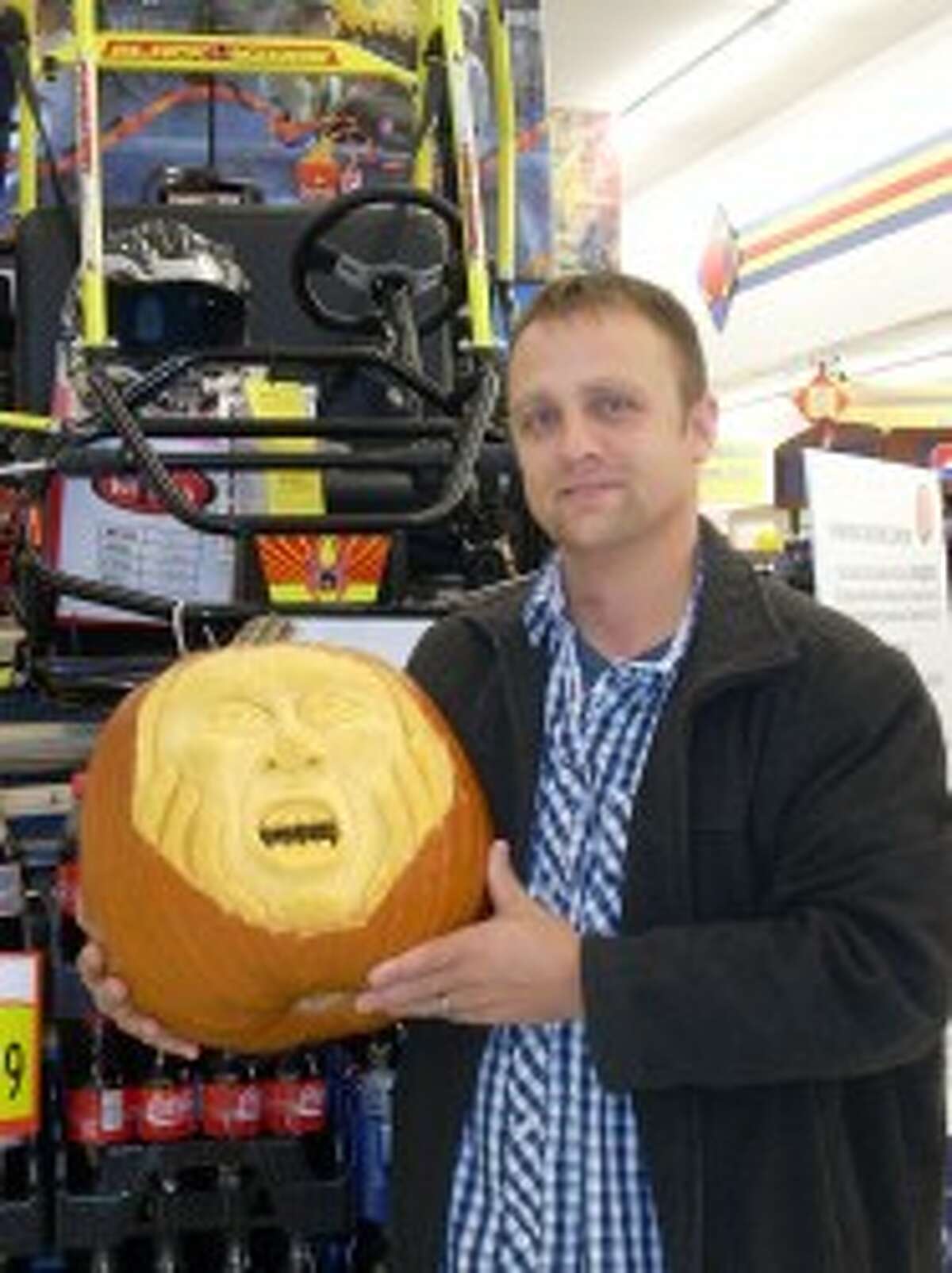 BEST PUMPKIN: Ryan Butler with his "Hands on Face Screaming Pumpkin" won first place in Leppink’s Grocery’s pumpkin decorating contest. He won the go-cart pictured at rear. (Courtesy photo)