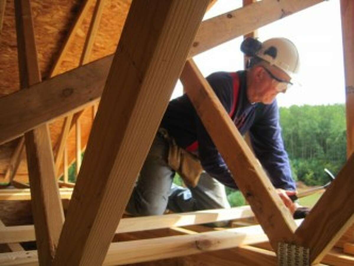 BUILD: A volunteer kneels on beams as he focuses on the task at hand. (Courtesy photo)