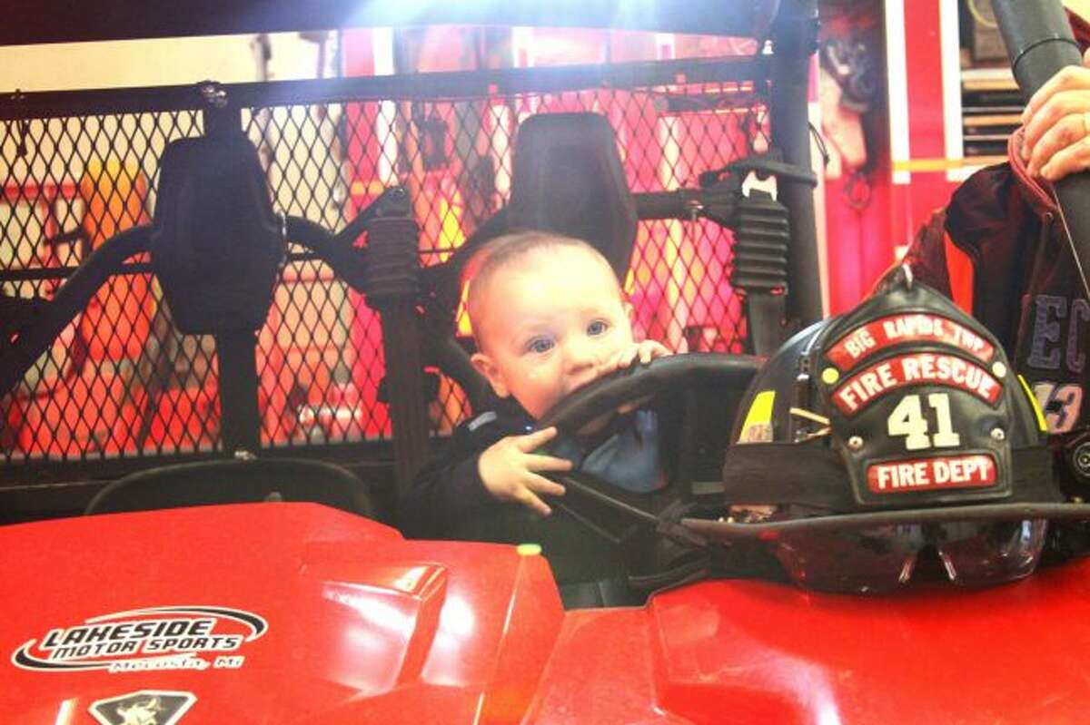 GOING FOR A RIDE: Little Dominyk Dukes shows his adventurous side as he pretends to drive Big Rapids Township Fire Department's off-road vehicle. (Pioneer photos/Meghan Haas)