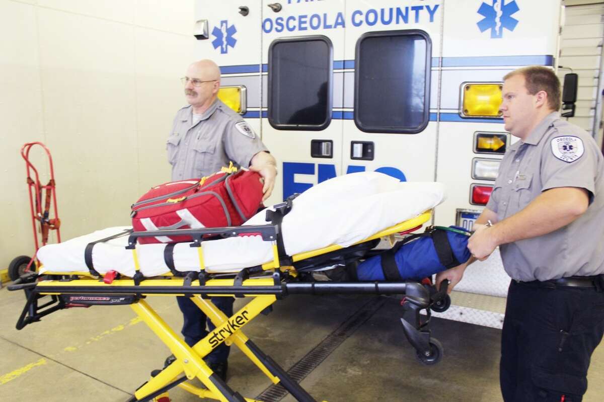 OSCEOLA COUNTY EMS: Lonnie Graham, EMT-basic, and Alan Taylor, paramedic, load equipment into an ambulance at the Osceola County EMS base in Reed City. Commissioners are considering new options to expand service to the northwest quadrant of the county. (Pioneer file photo)