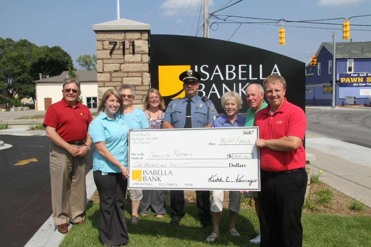 Isabella Bank Division President Keith Kenney, Branch Supervisor Felicia Donovan, Manna Food Pantry Coordinator Isabel Kempton, National Night Out Coordinator Linda Miller, DPS Sgt. Erik Little, Jeri and Ron Shubnell, of Angels of Action and Josh Eling, office manager and assistant vice president the bank located at 21440 Perry Avenue, hold a check for all the money Isabella Bank donated to nonprofits following the opening of a new branch.