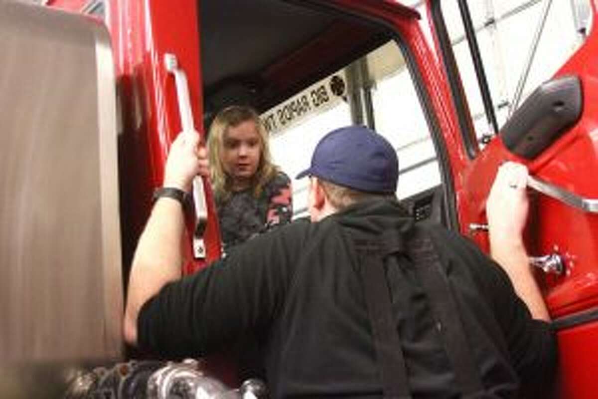 LEARNING SAFETY: Firefighter Steve Kopf teaches Carly Danielson (left) how to buckle up in the fire trucks and what some of the different buttons and gauges mean.