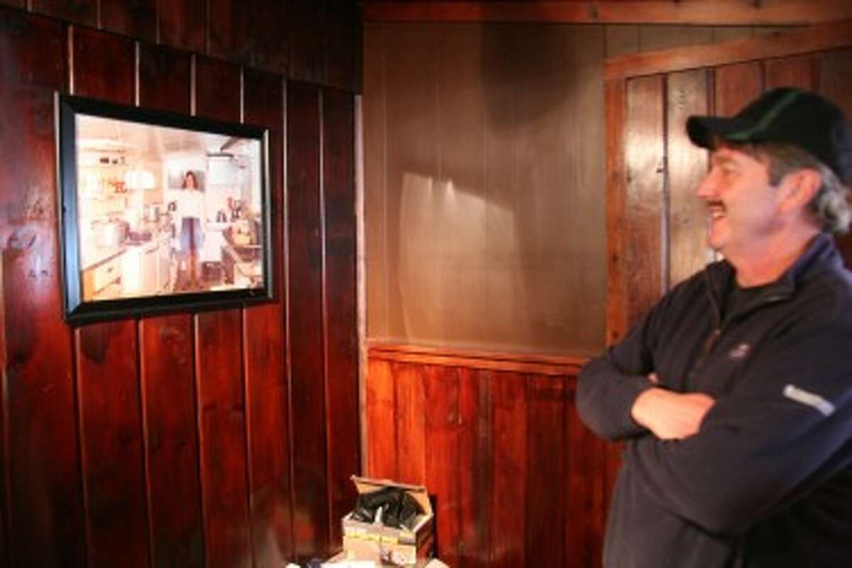 BOB THE BUILDER: Bob beardsley, co-owner of the soon-to-open Blue Lake Tavern looks at some of the old photographs that line the walls. The restaurant is located at 9899 11 Mile Road in Mecosta.