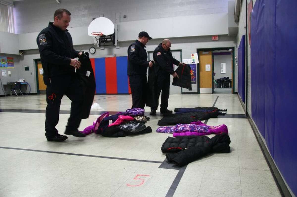MATCHMAKERS: Big Rapids firefighters arrange ten complete sets of snow jackets and pants in the gymnasium of Riverview Elementary in preparation for a number of students who received new snow gear. (Pioneer photo/Adam Gac)