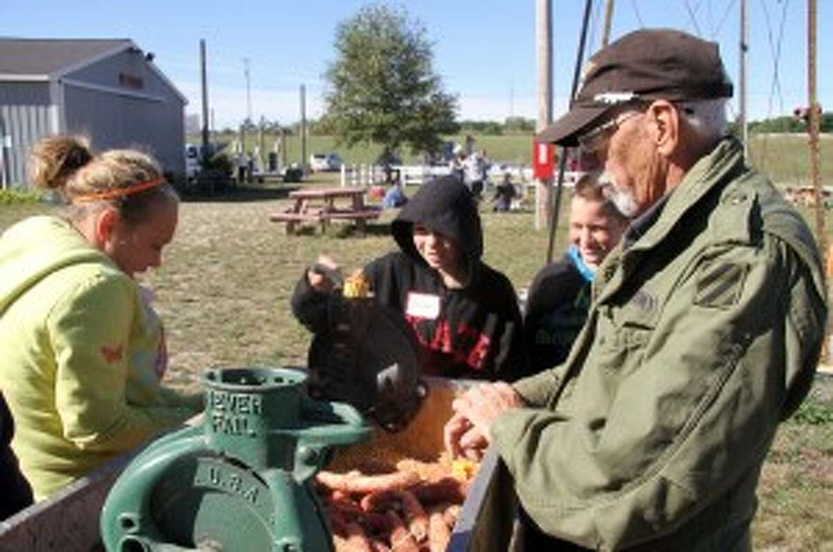 BACK IN TIME: Fifth-grade students shell corn the way it would have been done in the 1800s. Big Rapids Antique Farm and Power Club members let students try different types of farm and household work like it was done centuries ago.