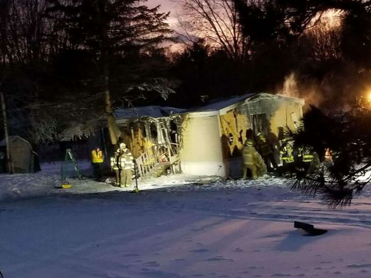 Firefighters work at the scene of a house fire Tuesday evening in Austin Township. The home was a total loss. (Courtesy photo)