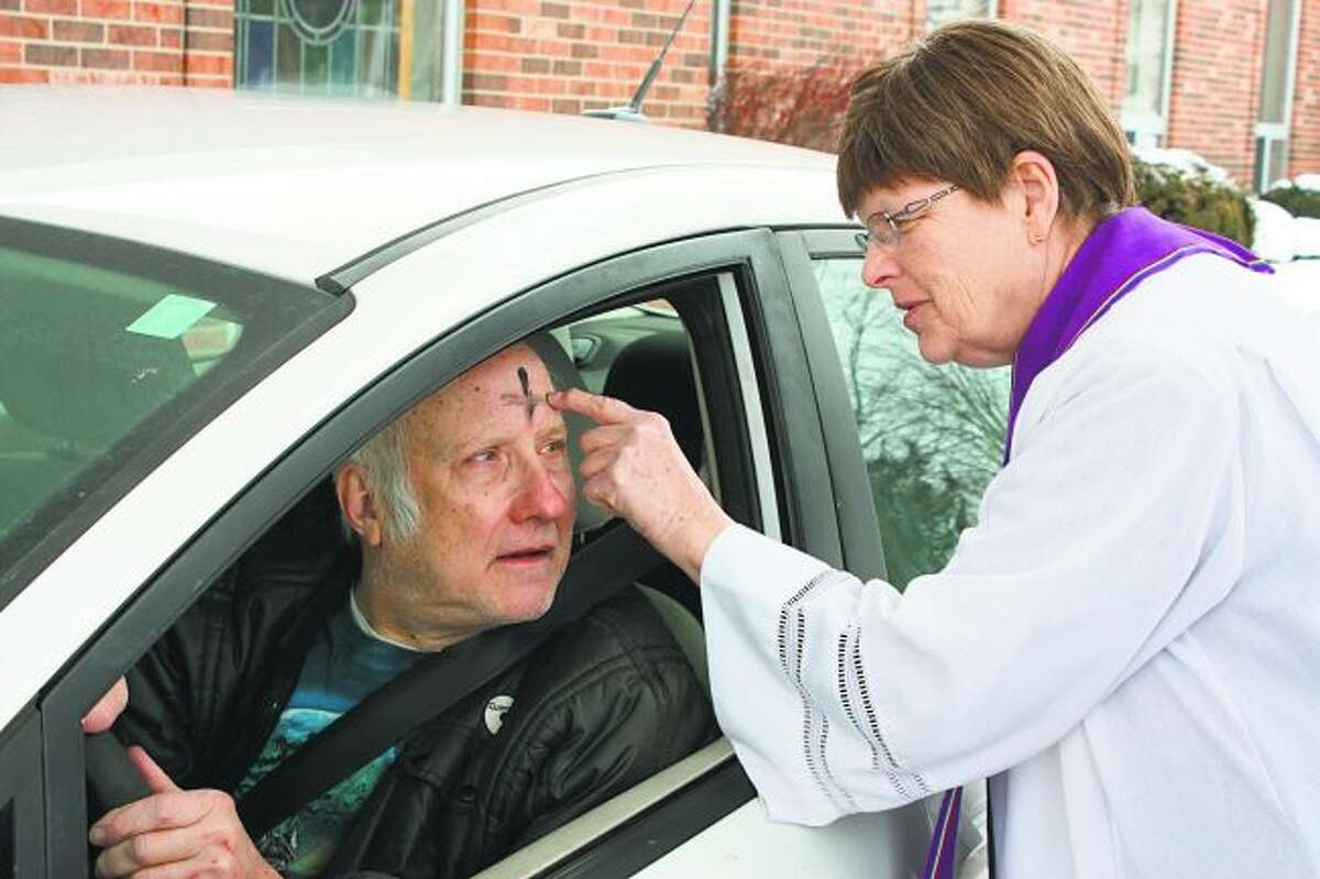 Mike Gibson, of Chippewa Lake, receives ashes on his forehead from his car on Wednesday from the Rev. Rebecca Morrison at First United Methodist Church in Big Rapids. The church offered a drive-thru service to mark Ash Wednesday, the traditional beginning of the Lenten season for Christians worldwide. (Pioneer photo/Tim Rath)