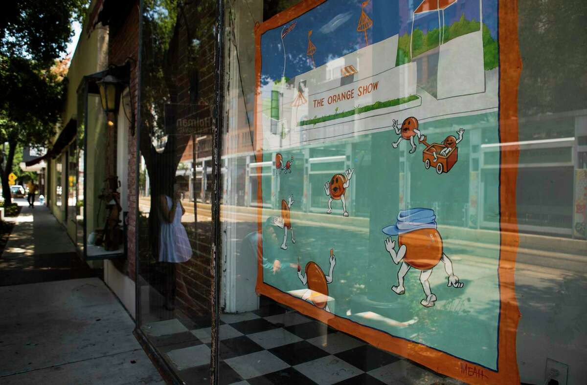 A tribute to the Orange Show hangs in the windows of a vacant building across from the Mid Main Lofts in Houston, Thursday, July 25, 2019. Lane and Bob Schultz have worked to fill much of the common areas along Main Street in that section of midtown with public art form murals to window displays in currently vacant buildings.