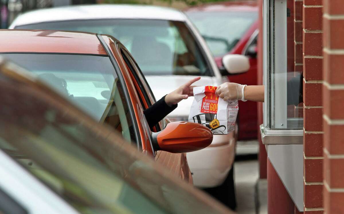 A worker serves a customer in the drive-up window of a McDonald’s.