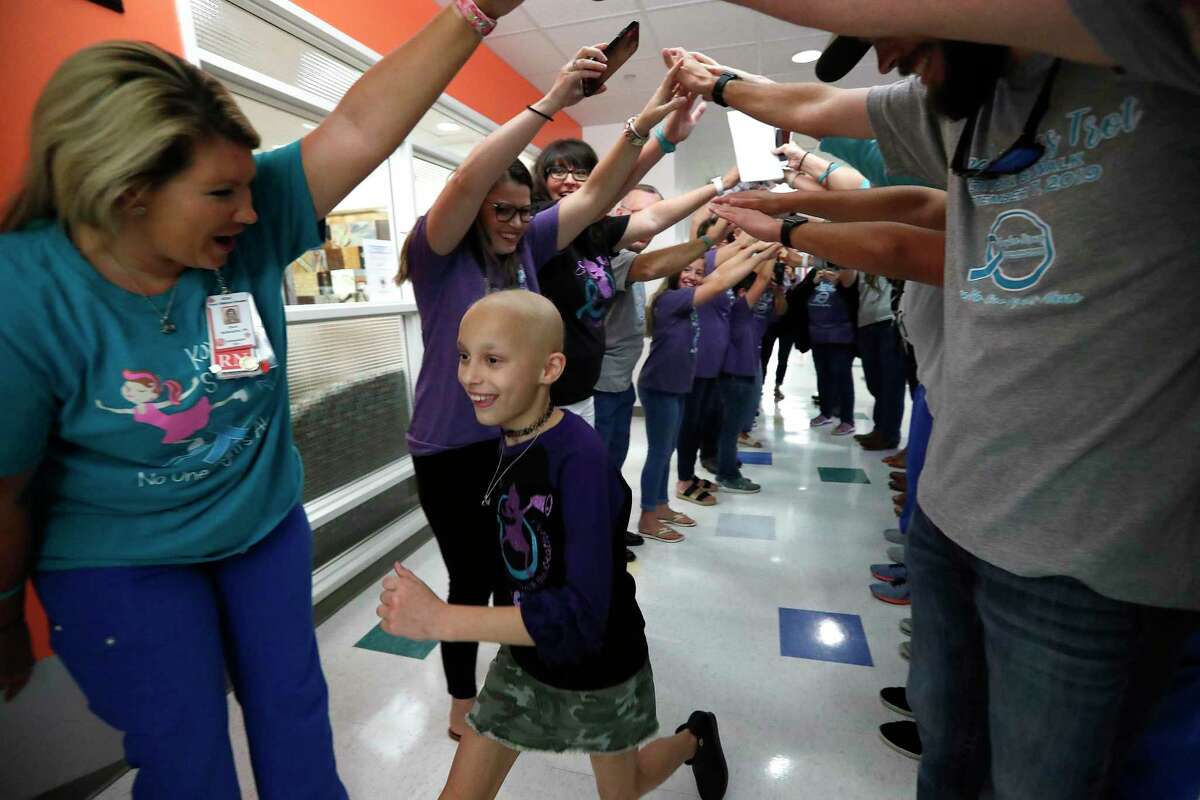Friends and family make a human arch as Kaylee Tolleson, 9, runs down the hall at Texas Children's Hospital to ring the bell signaling that she has finished cancer treatment.