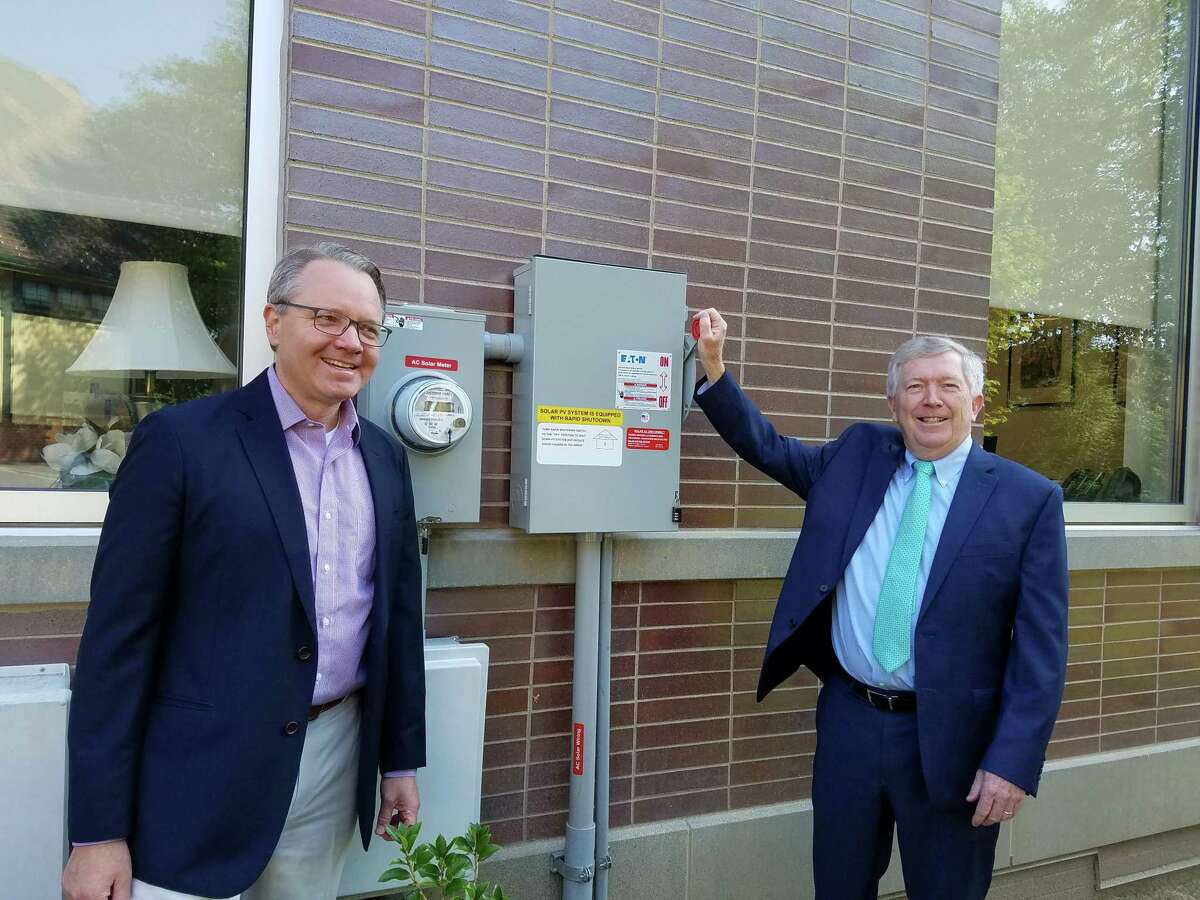 FIrst Selectman Kevin Moynihan raised the lever to turn on the 128 solar panels on the roof of New Canaan Town Hall over the summer. Cheering him on is Mark Robbins of MHR Development, LLC. Differences recently emerged between school officials, and the Selectmen’s Advisory Committee on Buildings and Infrastructure regarding getting solar power on the roofs of town schools.