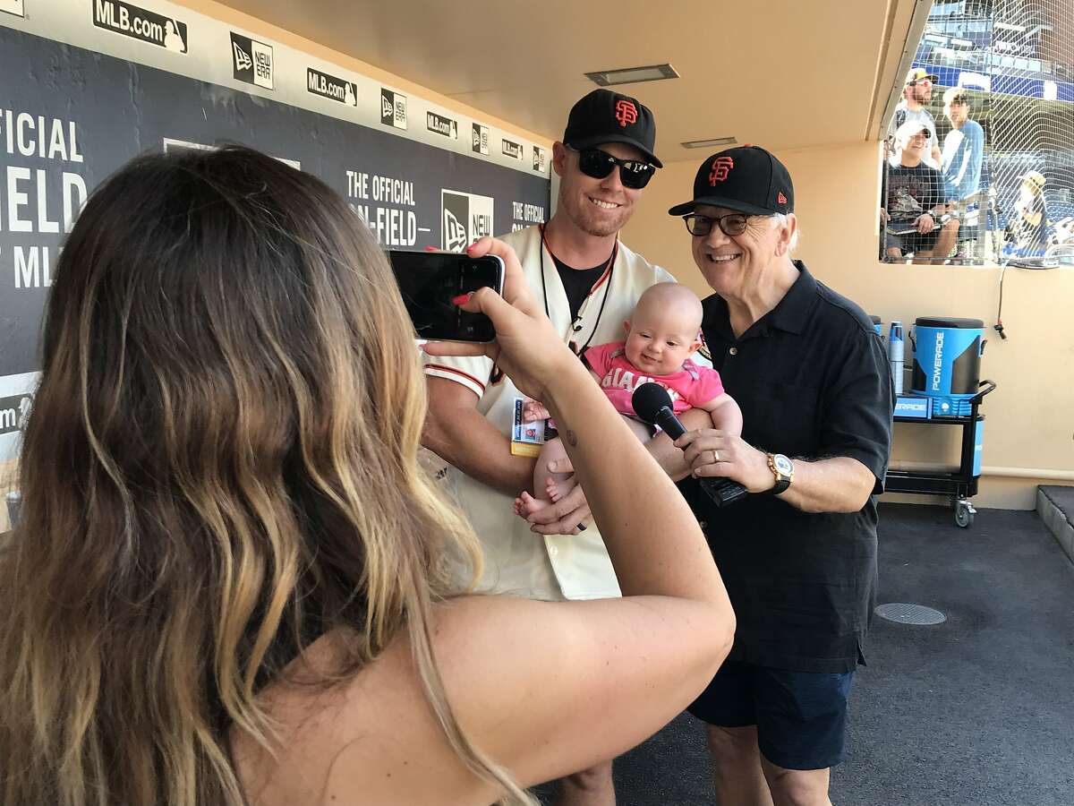 Chris Rice and Giants play-by-play announcer Jon Miller pose with Rice's 5-month-old daughter, Roya, as mother Neda Iranpour snaps a photo in the dugout before Saturday's game against the Padres. Rice's bare-handed catch of Pablo Sandoval's game-winning home run Friday night while holding Roya became an instant sensation.