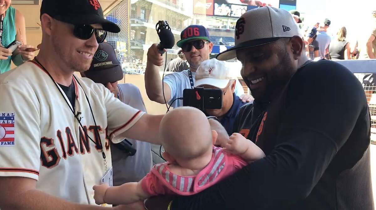 Chris Rice hands Giants second baseman Pablo Sandoval�his 5-month-old daughter, Roya, in the dugout before Saturday's game against the Padres at Petco Park in San Diego. Rice's bare-handed catch of Sandoval's game-winning home run Friday night while holding Roya became an instant sensation.