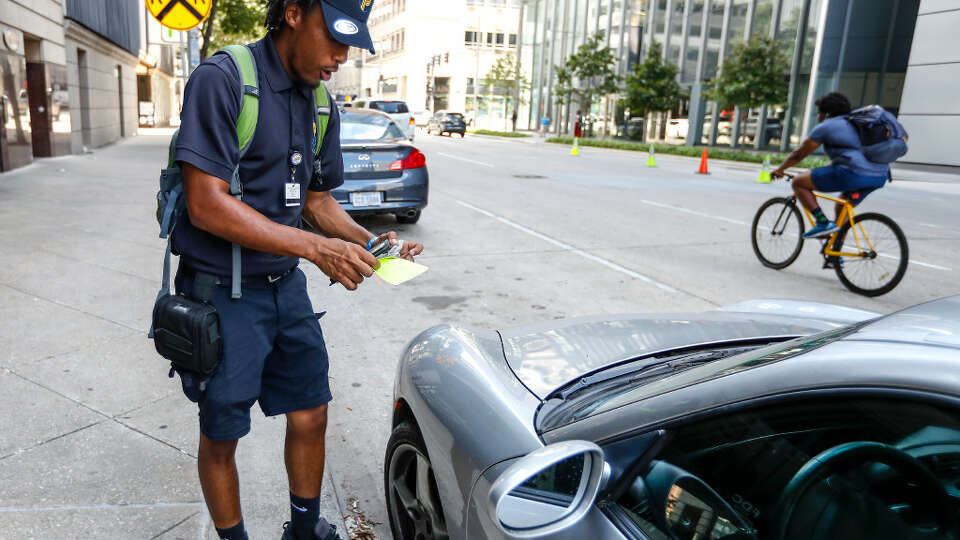 Morgan Metoyer, a city of Houston parking ticket officer, prepares to place a ticket on the windshield of a car parked in downtown Houston on lower Westheimer.