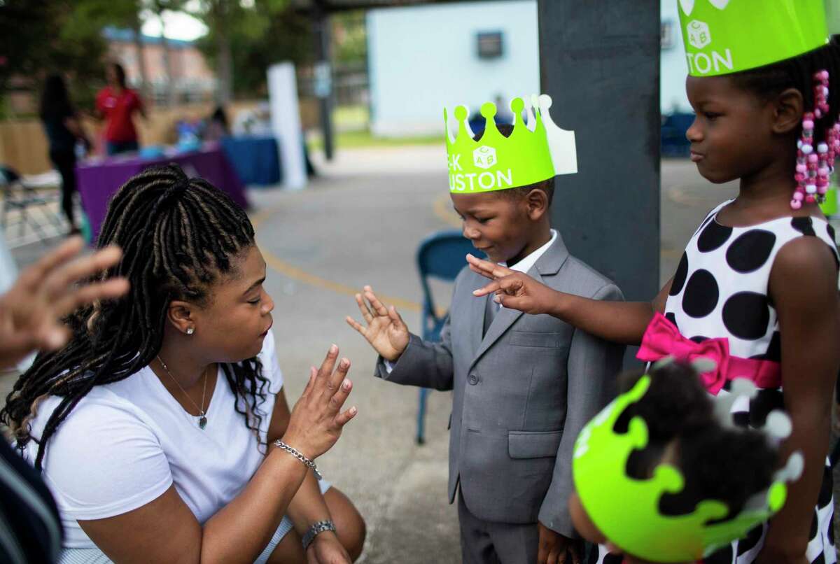 Wesley Elementary School assistant principal LaKia Jackson, left, asks Micah Shivers, 3, and his sisters Nyla Shivers, 5, and Paris Shivers, 2, for their ages during a visit to the Wesley Elementary School to possibly enroll Micah on Saturday, July 27, 2019, in Houston.