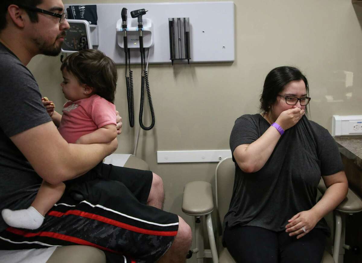 Ashley Elizondo, right, coughs while her, her husband, Nick, and their one-year-old daughter, Lyla, were examined at Harris County Public Health's mobile clinic on March 21, 2019, in Deer Park. The clinic was set up in response to the aftermath of the ITC petrochemical fire.