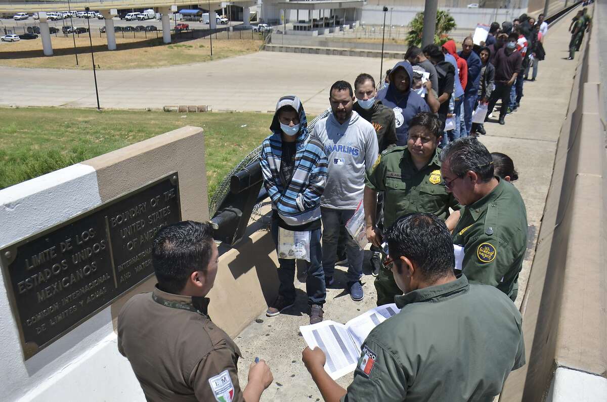 United States Border Patrol officers return a group of migrants back to the Mexico side of the border as Mexican immigration officials check the list, in Nuevo Laredo, Mexico, Thursday, July 25, 2019. Mexico has received some 20,000 asylum seekers returned to await U.S. immigration court dates under the program colloquially known as "remain in Mexico." (AP Photo/Salvador Gonzalez)