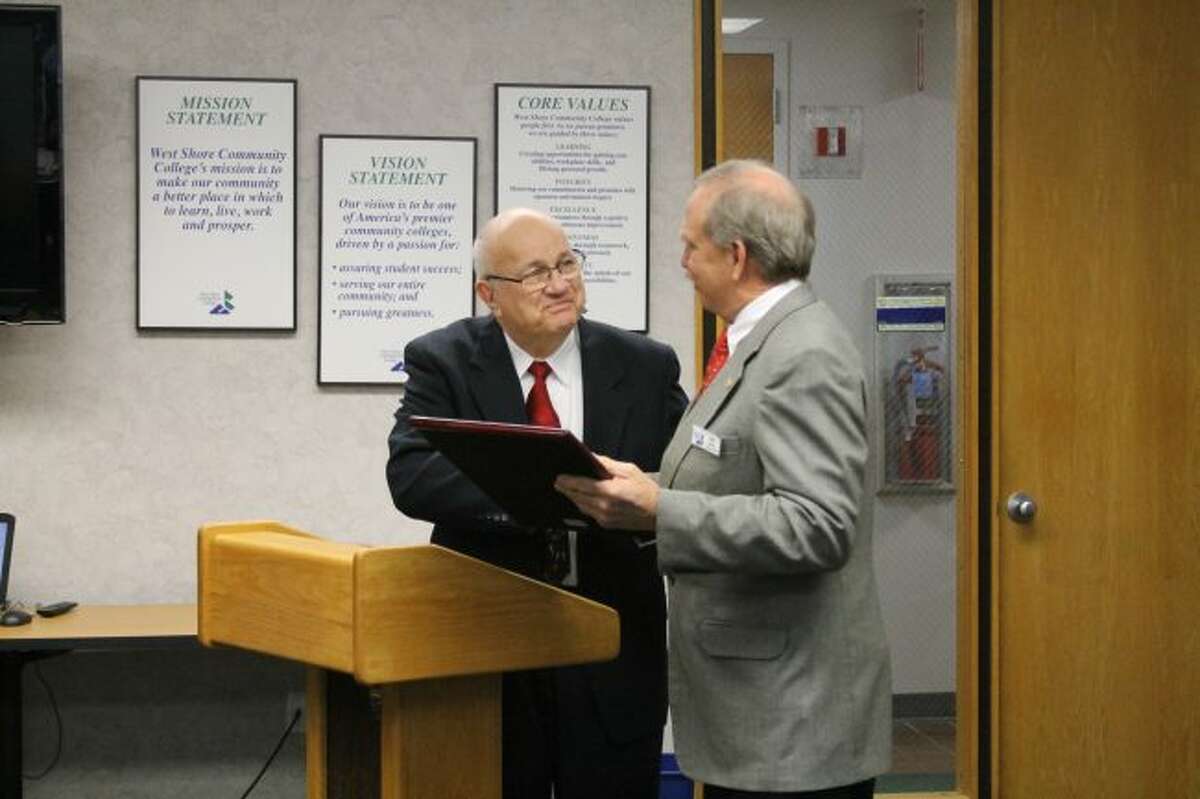 West Shore Community College Board of Trustees chair Bruce Smith (left) presents Mike Ennis with the proclamation he read at Monday's board meeting. The meeting was the last for Ennis who is retiring from the board after 20 years of service.