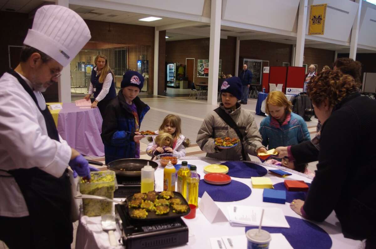 Food seemed to attract a good crowd throughout the evening at the LiveWell Expo at Manistee HIgh School. Here visiting chef Michael Hall of McClaren Hospital Lapeer prepares corn and kale skillet cakes on behalf of the West Shore Medical Center Cafe. (Dave Yarnell/News Advocate)