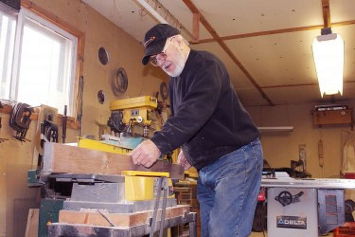 BUSY WORKSHOP: Jim Pylman, 79, of Evart, poses with a small selection of items he has made for his own use or pleasure. Furniture, picture frames, chests, toys, table centerpieces, collapsible baskets and more have been created throughout the years by his skill and talent. (Karin Armbruster/Herald Review photo)